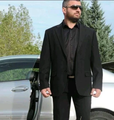 Michail Varsamis in executive protection attire beside a secure vehicle
